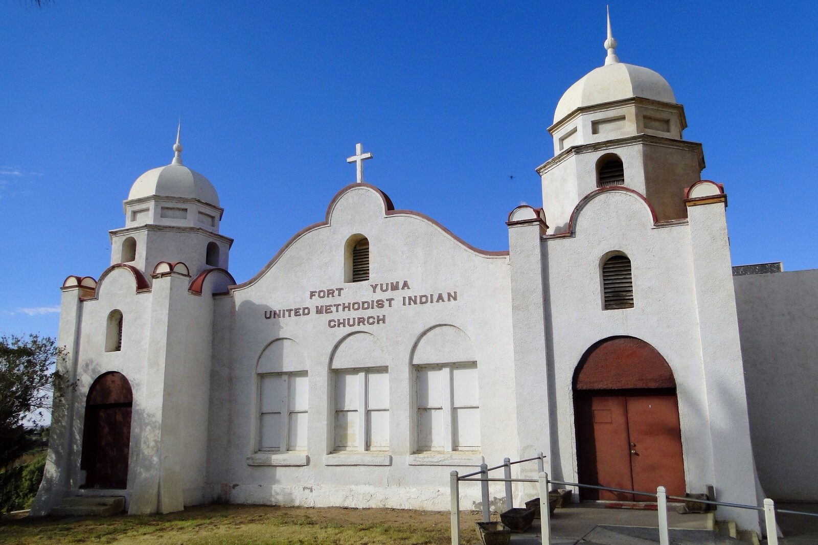 White mission-style Fort Yuma United Methodist Indian Church with twin towers under a blue sky in Winterhaven, California